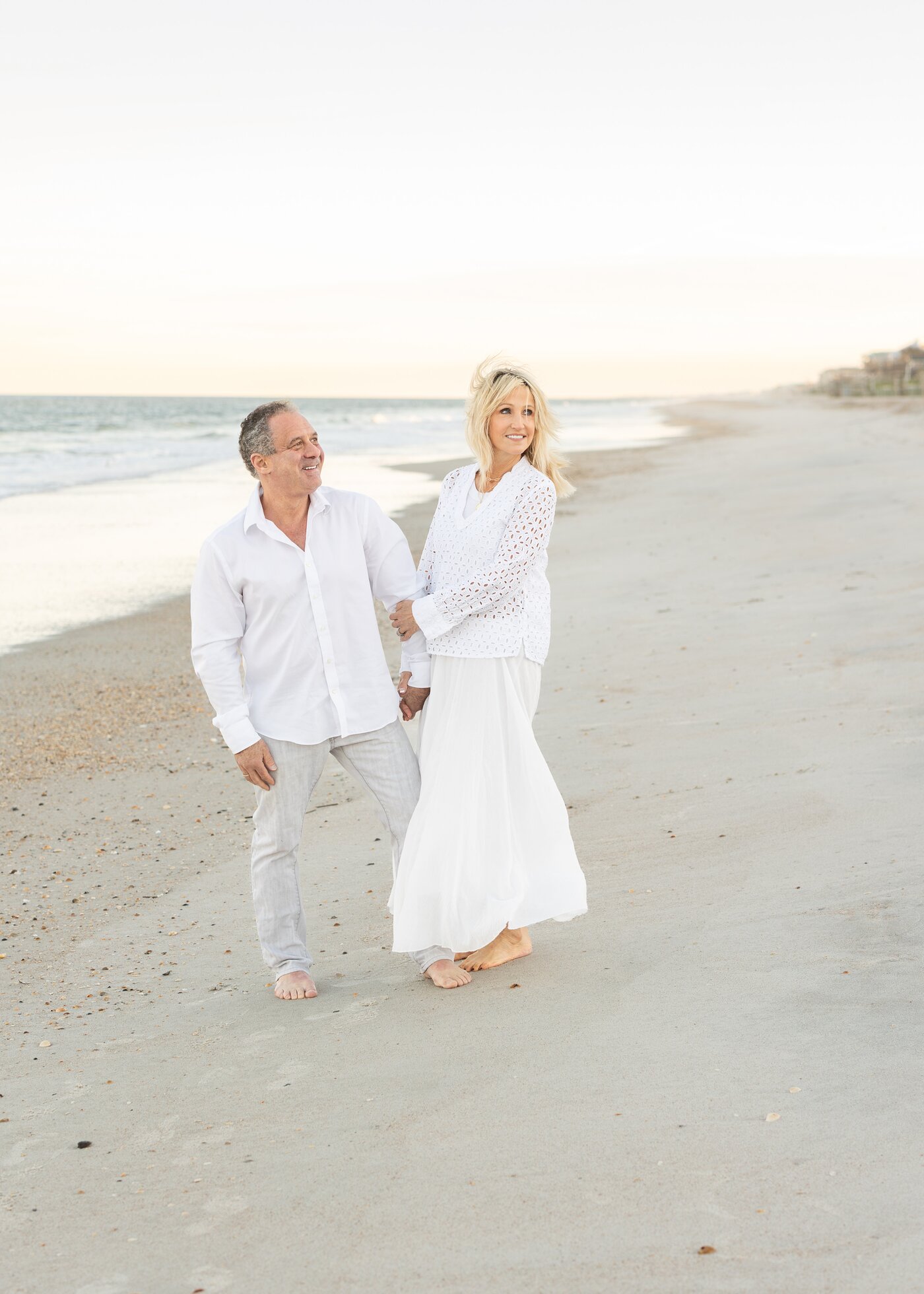 Lori and Steve Gordon walking on the beach at sunset